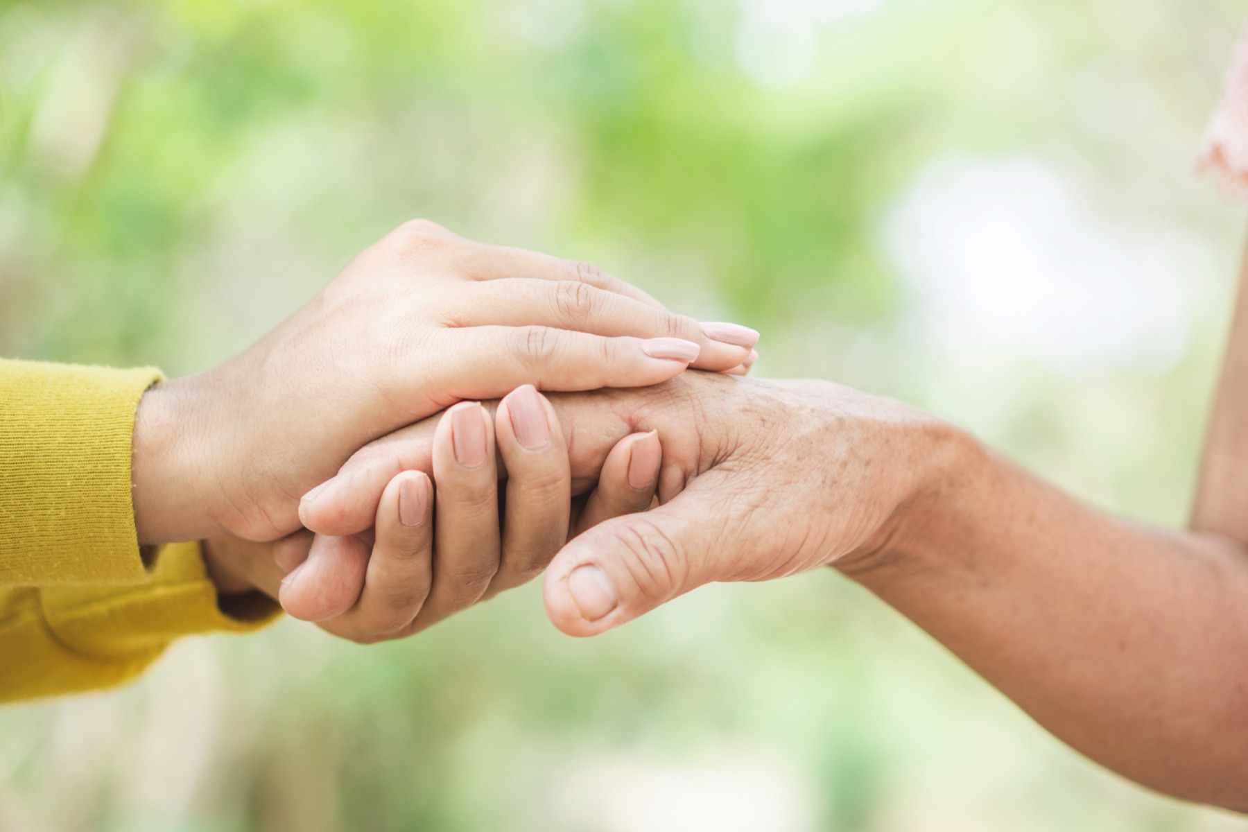 Eine junge Hand hält die Hand einer älteren Person